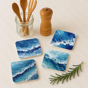 May include: Set of four square coasters with a blue and white ocean wave design. The coasters are made of a durable material and are perfect for protecting surfaces from water rings. A wooden salt shaker, utensils, and rosemary sprig are also in the image.