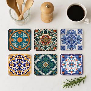 Może przedstawiać: Sześć kwadratowych podkładek z misternymi, kolorowymi wzorami kwiatowymi i geometrycznymi. Podkładki mają odcienie niebieskiego, pomarańczowego, zielonego i żółtego. Widoczna jest również filiżanka kawy, drewniane łyżki i młynek do pieprzu.