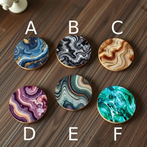 A labeled set of six gemstone-inspired coasters, each featuring intricate marbled patterns in luxurious hues of deep blue, emerald green, and rich burgundy.