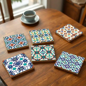 Op de afbeelding: Zes kleurrijke keramische onderzetters met ingewikkelde geometrische patronen in tinten blauw, oranje en wit. De onderzetters zijn gerangschikt op een houten tafel.