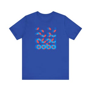 May include: Royal blue t-shirt with a geometric pattern in red and blue. The design is made up of layered semi-circles in a grid. The shirt is made of a soft, comfortable material.