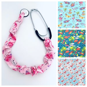 May include: A pink stethoscope with a flamingo print. The stethoscope has a black rubber tube and a silver metal head. The flamingo print is pink and white and features flamingos standing on one leg.