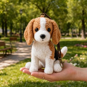 May include: A plush beagle dog keychain featuring a textured, fuzzy white, brown, and black coat with large black eyes and a black nose. The stuffed animal has long, floppy ears and is attached to a dark brown braided cord with a metal lobster clasp.