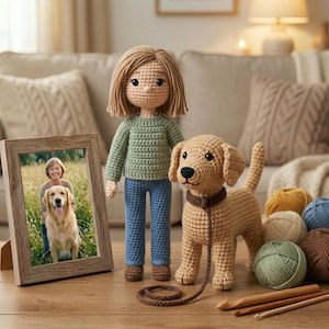 May include: A crochet doll with light brown hair wearing a sage green sweater and blue pants, standing next to a tan crochet dog with a dark brown collar and leash. A wooden picture frame displays a photo of a person and a golden retriever.