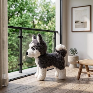 May include: A plush stuffed animal shaped like a husky dog, featuring a textured dark gray and white coat, a curled tail, and large black eyes. The toy stands on four legs and has a white face with dark gray patches around the ears and eyes.