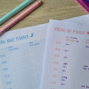 May include: A white nursing planner with a blue moon icon and the text "Nursing Night Planner". The planner has columns for time, name, and room number. A pink pen is lying on top of the planner.