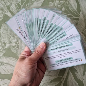 May include: A set of flashcards with green and white backgrounds. The cards contain information about nursing abbreviations, fluid requirements, drug calculations, and weight-based doses. The text on the cards reads "Standard Drug Calculation", "NEED + HAVE = SOLUTION", "Weight-based Doses", and "Dosage = Patient weight kg x what you need".