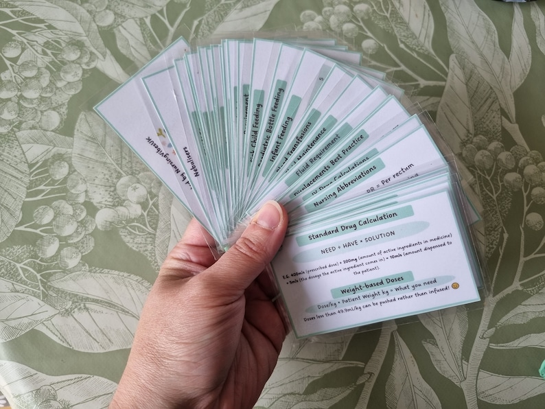 May include: A set of flashcards with green and white backgrounds. The cards contain information about nursing abbreviations, fluid requirements, drug calculations, and weight-based doses. The text on the cards reads "Standard Drug Calculation", "NEED + HAVE = SOLUTION", "Weight-based Doses", and "Dosage = Patient weight kg x what you need".