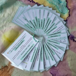 May include: A set of green and white flashcards with medical terms and calculations. The cards are fanned out in a circle, with the text facing outward. The cards include terms such as "Standard Drug Calculation", "Fluid Maintenance", "Nursing Abbreviations", and "Weight-based Doses".