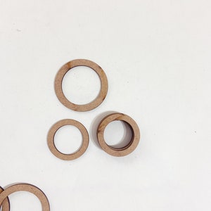 May include: Three wooden rings of different sizes. The rings are all brown and have a smooth finish.