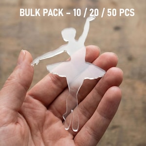Può includere: Sagoma trasparente di ballerina in plastica, tenuta in mano. La ballerina è in posa di danza con un braccio alzato. Il testo "BULK PACK - 10 / 20 / 50 PCS" è visibile in alto.