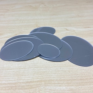 Pode incluir: Um conjunto de sete discos cinzentos ovais de tamanhos diferentes, empilhados uns sobre os outros.