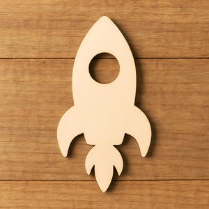 May include: A wooden rocket ship cutout with a circular window and flame detail. The rocket is made of light-colored wood and is set against a wooden background. This craft is ideal for crafting projects.