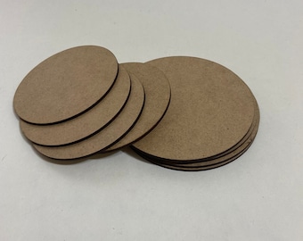 May include: A collection of unfinished, round wooden craft blanks. The blanks are various sizes and are made of a light brown material. The edges are dark brown. The blanks are stacked and scattered on a white surface.
