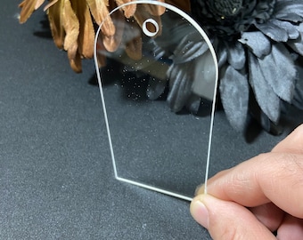 May include: A clear acrylic tag with a rounded top and a hole for a string or ribbon. The tag is blank and ready to be personalized.