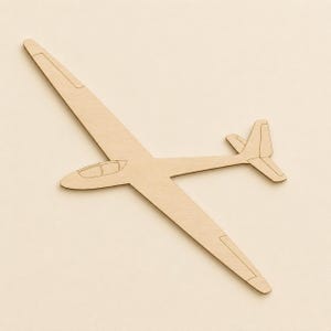 Könnte beinhalten: Ein flacher, hellfarbener Holzausschnitt in Form eines Segelflugzeugs. Die Silhouette zeigt lange, schmale Flügel, einen stromlinienförmigen Rumpf, die Umrisse einer Cockpithaube und ein T-förmiges Leitwerk mit eingravierten Linien an den Flügeln.