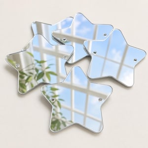 Puede incluir: Un conjunto de cinco espejos con forma de estrella y superficies lisas y reflectantes. Cada espejo de estrella individual presenta dos pequeños orificios circulares preperforados cerca de las puntas superiores, lo que facilita su fijación.