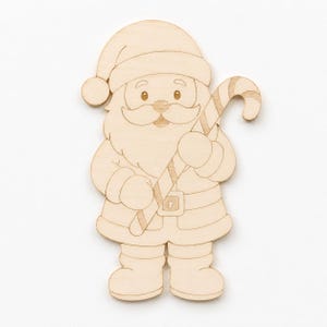 Può includere: Una sagoma in legno di colore chiaro raffigurante Babbo Natale con cappello, giacca con cintura e stivali. La figura ha una lunga barba e tiene un bastoncino di zucchero a righe in diagonale. Il design presenta linee incise per i dettagli.