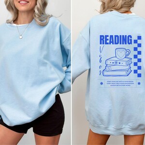 a woman wearing a blue sweatshirt with reading on it