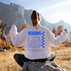 a woman sitting on a rock reading a book