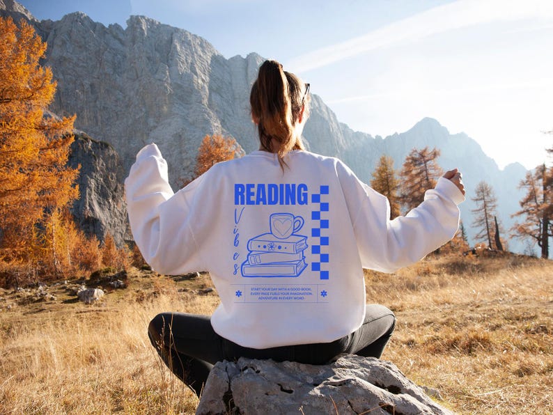 a woman sitting on a rock reading a book