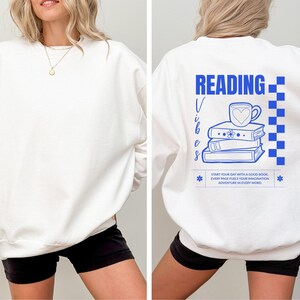 a woman wearing a white sweatshirt with reading on it