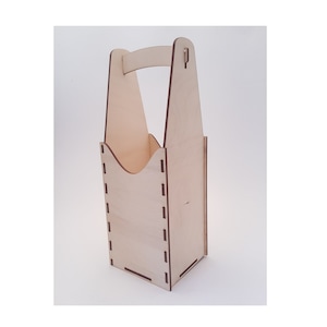 May include: A wooden bottle carrier with a handle. The carrier is made of light brown wood and has a cutout for a bottle. The carrier has a decorative design with a dashed line pattern.