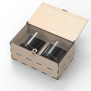 May include: A wooden box with a hinged lid, containing two clear glass tumblers. The box is made of light wood and has a simple design.