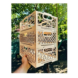 Puede incluir: Tres cajas de madera apiladas una encima de la otra. Cada caja tiene un diseño diferente cortado con láser. La caja superior tiene un diseño de vid, la caja del medio tiene un diseño geométrico y la caja inferior tiene un diseño de panal.