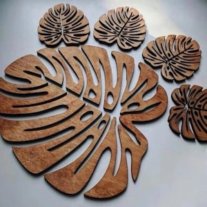 May include: Set of six wooden coasters featuring a tropical leaf design. The coasters are brown and have a natural wood finish.