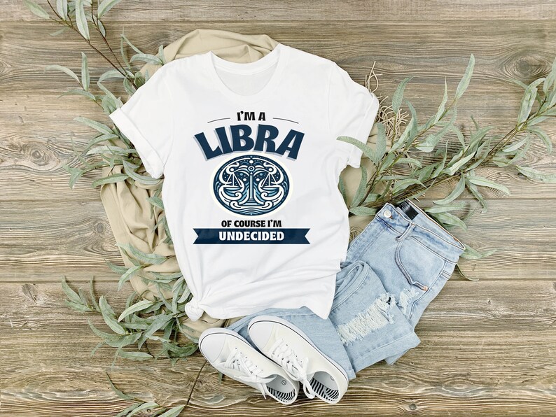 May include: White t-shirt with a blue Libra zodiac symbol and the text "I'm a Libra, of course I'm undecided."