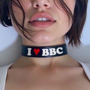 May include: A black choker with the text "I ❤️ BBC" in white lettering and a red heart. The choker is approximately 14 inches in length. The design proportion may look different on longer collars.