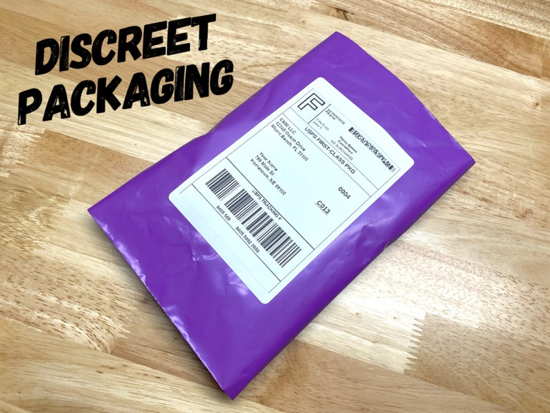 May include: A purple padded envelope with a white shipping label. The label has the text "USPS First Class PKG" and a tracking number. The envelope is on a wooden surface.