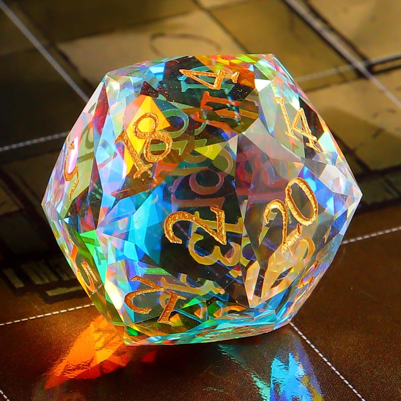 May include: A multi-faceted iridescent crystal d20 dice with gold numbers. The dice is a twenty-sided die used in tabletop role-playing games.