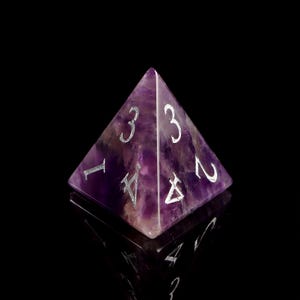 May include: A purple amethyst pyramid-shaped dice with silver numbers 1, 2, 3, and 4.