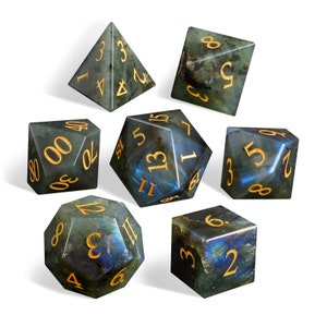 May include: Set of seven blue and green gemstone dice with gold numbers. The dice are in various shapes, including a pyramid, a cube, and a dodecahedron.