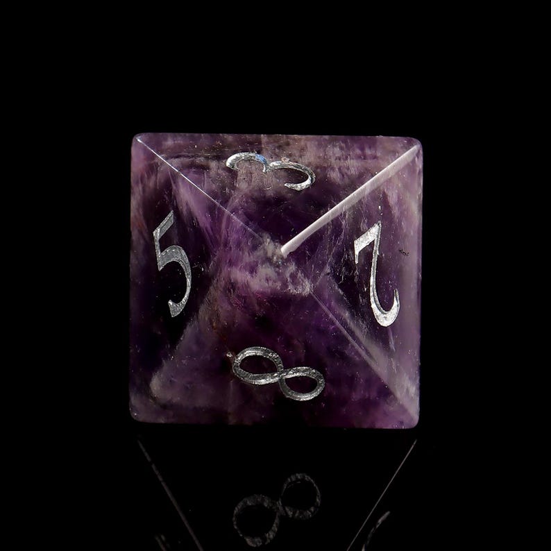 May include: A purple amethyst gemstone dice with silver numbers 5, 7, and an infinity symbol.