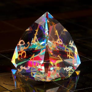 May include: A multi-faceted iridescent crystal dice with gold numbers. The dice is shaped like a pyramid and has a rainbow effect.