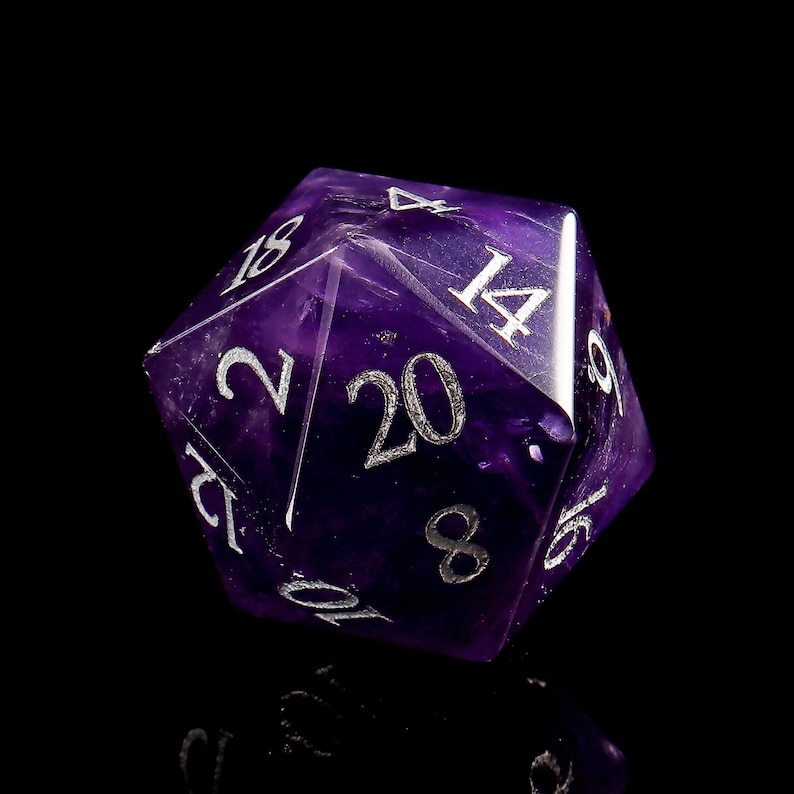 May include: A purple 20-sided die made of amethyst with silver numbers. The die is showing the number 20.