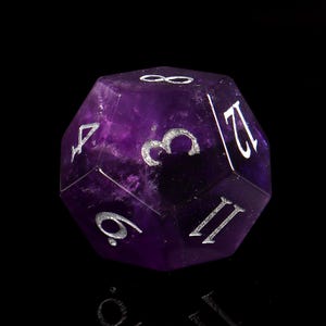 May include: A purple amethyst gemstone twelve-sided die with silver numbers 1 through 12.