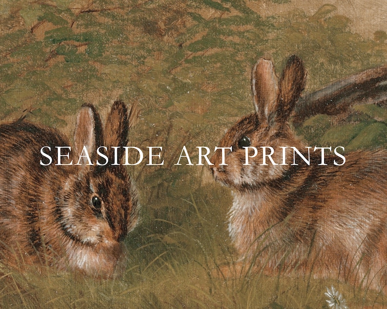 Op de afbeelding: Een schilderij van twee bruine konijnen in een grasveld. De konijnen kijken in verschillende richtingen. De tekst "SEASIDE ART PRINTS" is in het midden van de afbeelding gedrukt.
