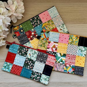 May include: Two patchwork zipper pouches in a variety of patterns, including floral, polka dots, and alphabet designs. The pouches have black and red zippers and are arranged on a light wooden surface. The pouches are a mix of red, blue, yellow, and green.