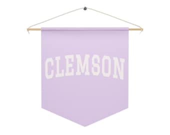 May include: A light purple pennant banner with the word "CLEMSON" in white block letters. The banner is suspended from a wooden rod and string.