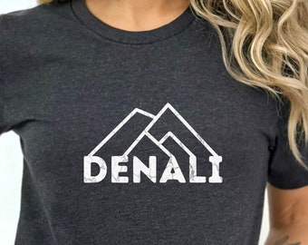 May include: A dark heather grey t-shirt with a white graphic of a mountain range and the word "DENALI" printed on the front.