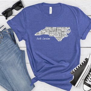 Pu&ograve; includere: Una maglietta blu con un contorno bianco dello stato della Carolina del Nord. Il contorno &egrave; riempito con parole relative alla Carolina del Nord, come "Tar Heel", "Biscuits" e "Appalachian". Le parole "North Carolina" sono stampate sotto il contorno.