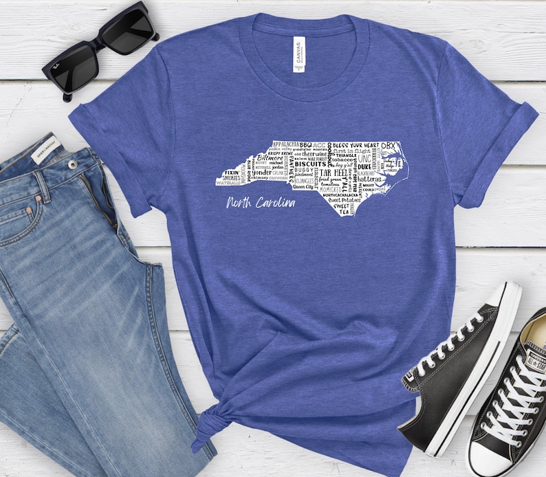 Pu&ograve; includere: Una maglietta blu con un contorno bianco dello stato della Carolina del Nord. Il contorno &egrave; riempito con parole relative alla Carolina del Nord, come "Tar Heel", "Biscuits" e "Appalachian". Le parole "North Carolina" sono stampate sotto il contorno.