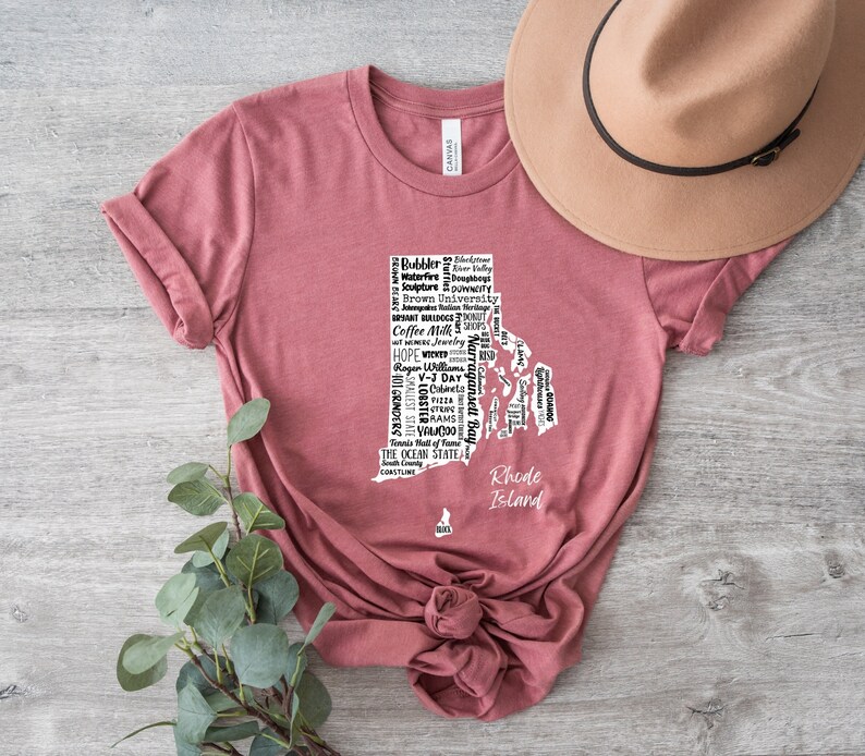 K&ouml;nnte beinhalten: Ein maronfarbenes T-Shirt mit einer wei&szlig;en Umrandung des Bundesstaates Rhode Island. Die Umrandung ist mit Text gef&uuml;llt, der sich auf Rhode Island bezieht, darunter "Coffee Milk", "Ocean State", "Hope", "Providence", "Newport" und "Block Island". Der Text "Rhode Island" steht unterhalb der Umrandung.