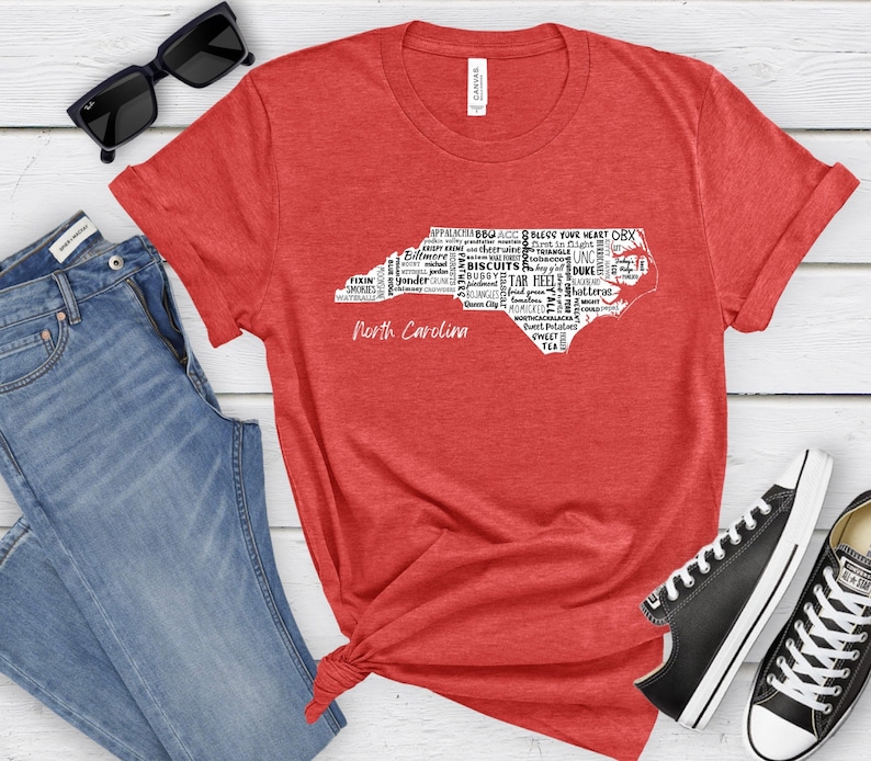 Pu&ograve; includere: Maglietta rossa con un contorno bianco dello stato della Carolina del Nord. Il contorno &egrave; riempito con parole relative alla Carolina del Nord, come "Tar Heels", "Duke", "Biscuits", "Smokies", "Yonder" e "Appalachia".