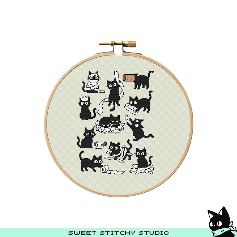 May include: A cross-stitch embroidery hoop featuring a playful design of black cats in various poses. The cats are depicted with simple, cartoon-like features, interacting with objects like toilet paper rolls and crowns. The hoop is made of wood and has a light beige fabric background.