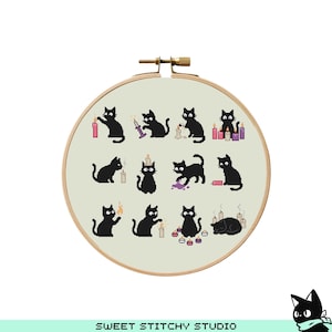May include: A cross-stitch embroidery hoop featuring a light beige fabric with a repeating pattern of black cat silhouettes interacting with candles. The wooden hoop has a brass-colored clasp. The text "SWEET STITCHY STUDIO" is at the bottom.